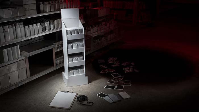 Expositor de PLV iluminado en una tienda oscura mientras las fotografías, los controles y el stock desaparecen en un agujero negro, simbolizando la falta de evidencias para medir el retorno de la campaña.